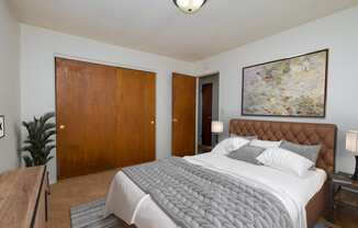 a bedroom with a large bed and a painting on the wall. Fargo, ND North Manor Apartments