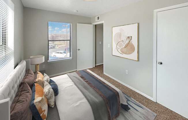 A bedroom with a bed, a window, and a painting on the wall.