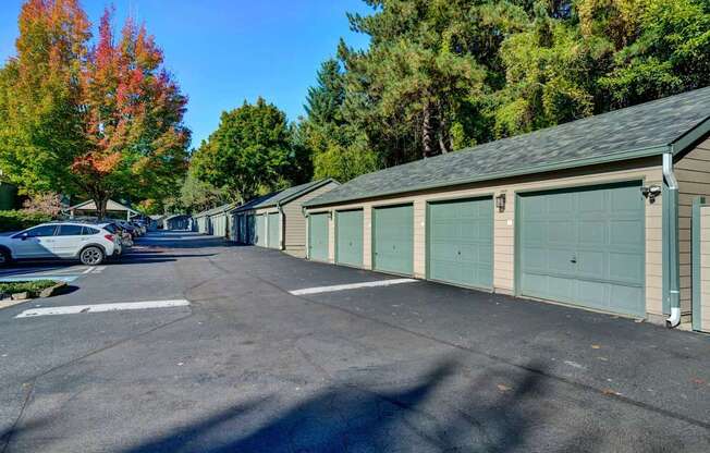 A parking lot with a car parked and a building with a green garage door.