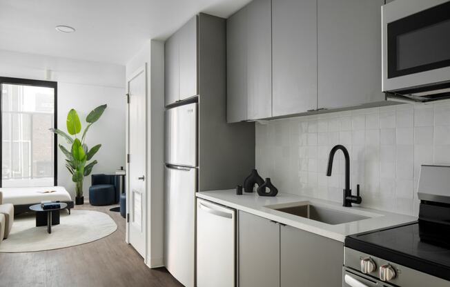 a kitchen and living room with white cabinets and a sink