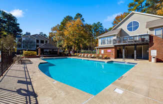 A large swimming pool in front of a house with a deck.