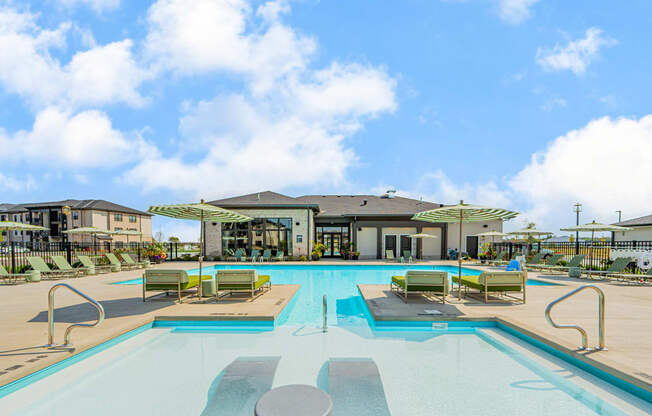 a swimming pool with lounge chairs and a building in the background