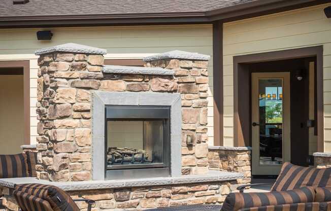 a patio with chairs in front of a building with a fireplace