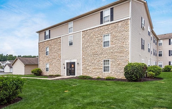A large building with a black door and windows surrounded by a green lawn.