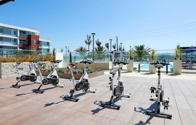 a group of exercise bikes parked on a patio near a pool