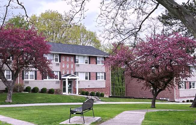 a bench sits in the middle of a grassy area in front of a brick building