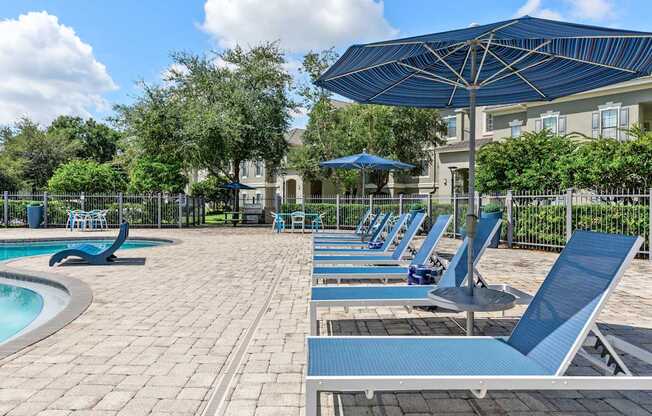 A pool area with sun loungers and a blue umbrella.