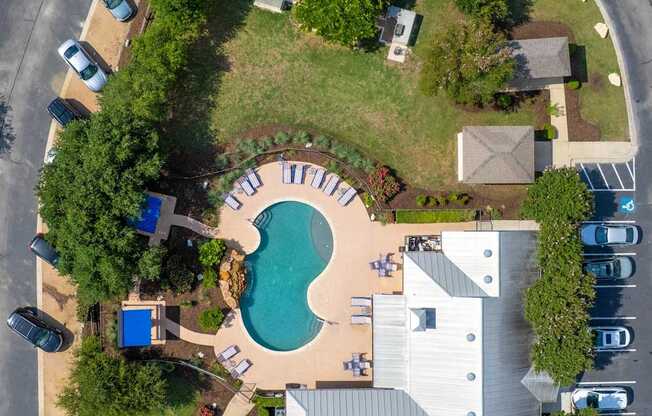 A bird's eye view of a residential area with a swimming pool and a house.