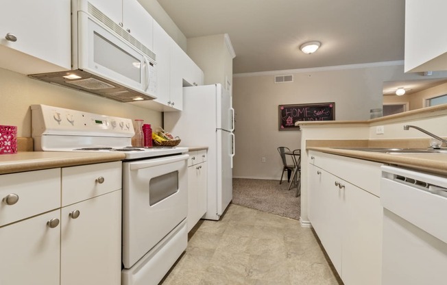 a kitchen with white appliances and counters and a dining room with a table