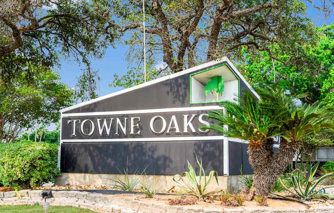 A sign that says "Towne Oaks" is in front of a tree.