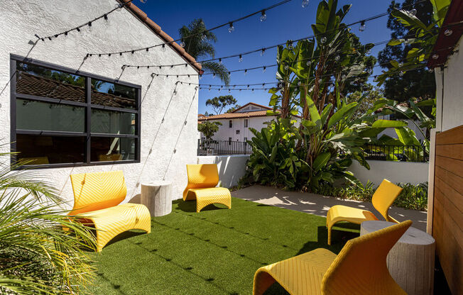 a backyard with yellow chairs and a green lawn at La Jolla Blue, San Diego, CA 92122