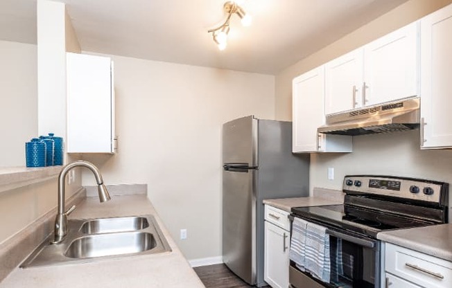 A kitchen with a stainless steel refrigerator, oven, and sink.