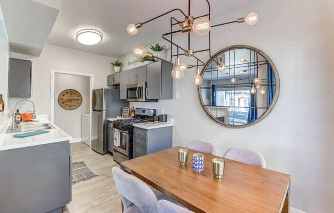 a dining area with a table and chairs and a kitchen in the background