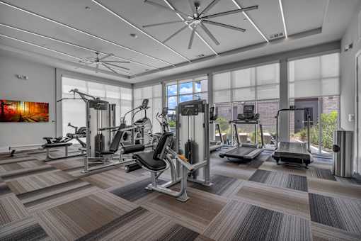A spacious gym with a variety of equipment and a ceiling fan.