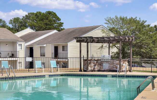 A swimming pool with a slide and chairs in front of a house.