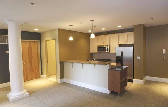 an empty kitchen and living room with a counter and refrigerator