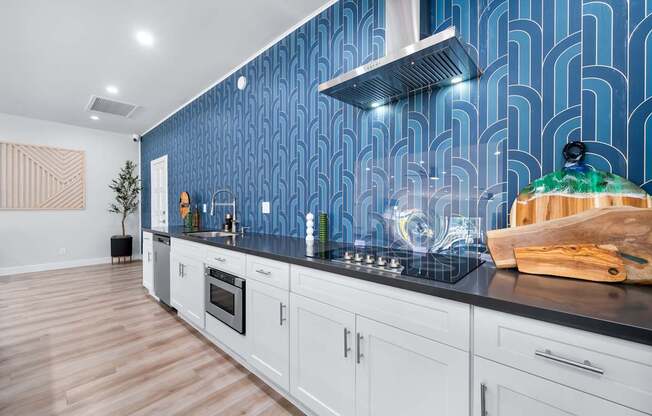 A kitchen with white cabinets and a blue backsplash.