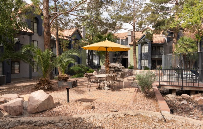 a patio with tables and an umbrella in a courtyard