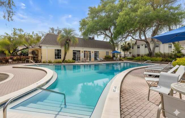 A swimming pool surrounded by lounge chairs and trees.