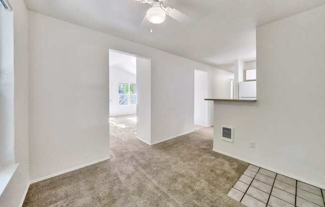 an empty living room with carpet and a ceiling fan