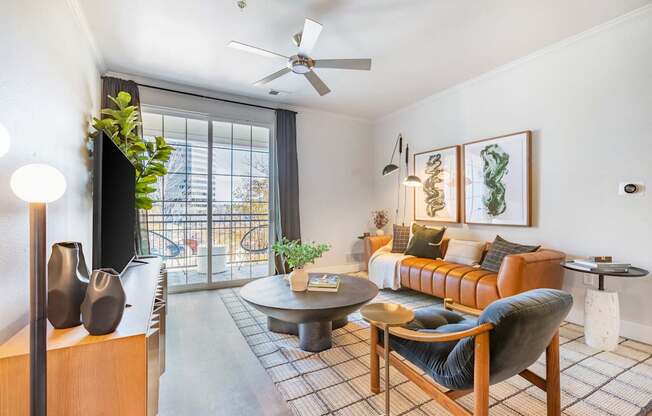 A living room with a brown couch, a grey armchair, a coffee table, and a ceiling fan.