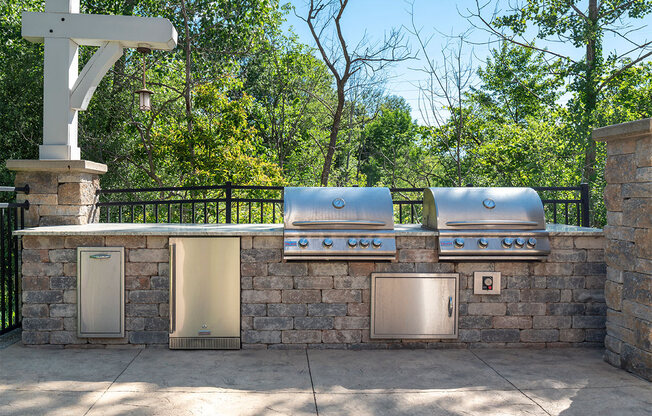 an outdoor kitchen with stainless steel appliances and a stone wall