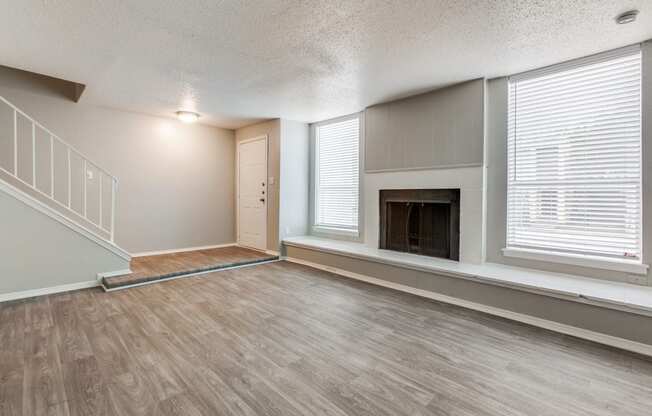 an empty living room with a fireplace and a staircase