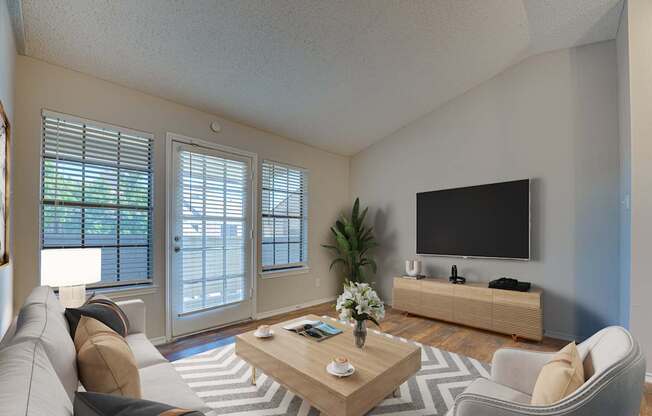 A living room with a grey couch, a wooden coffee table, a flat screen TV and a plant.