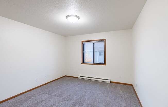 a bedroom with carpet and a window. Fargo, ND Flagstone Apartments