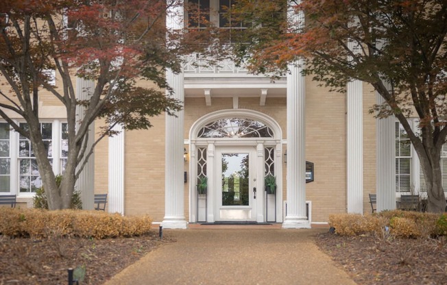 a white door on a brick building with trees in front of it