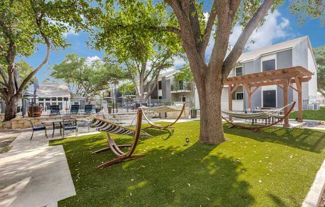 A park with a bench and a tree in front of a building.