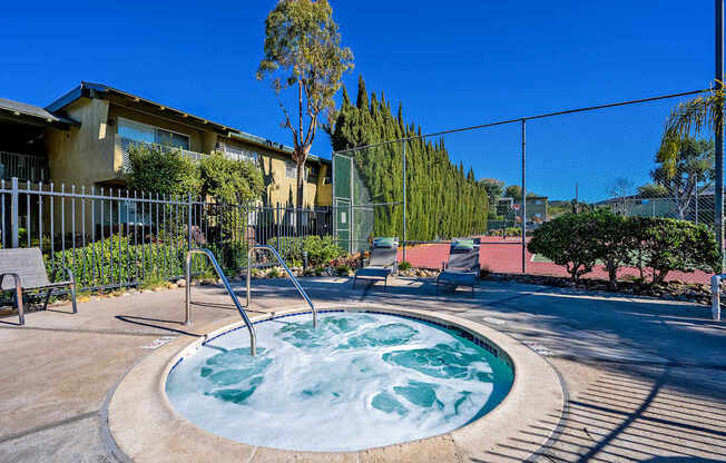 A hot tub sits in the middle of a patio surrounded by a fence.