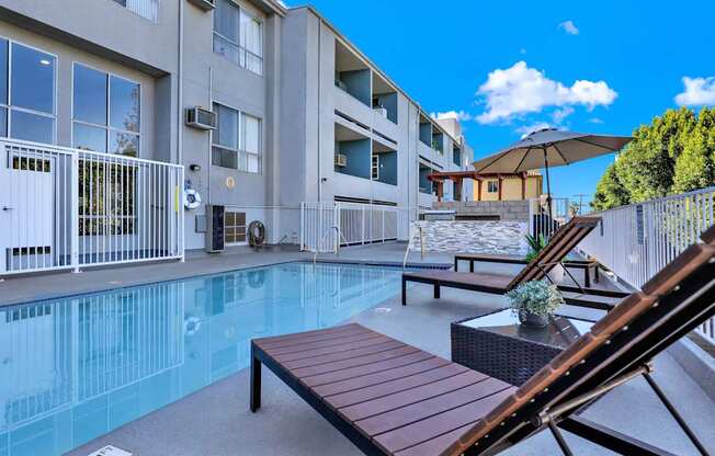 A pool area with a bench and a table with a potted plant on it.