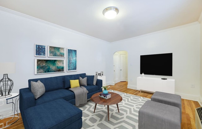 living area with sofa, coffee table, credenza, tv, hardwood flooring and modern artwork at 3213 wisconsin apartments in washington dc