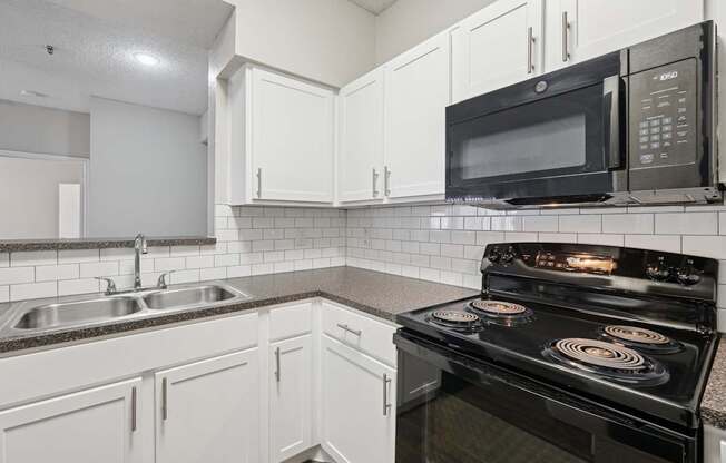 B1 kitchen with black appliances and white cabinets at Jefferson Place Apartments in Irving, TX
