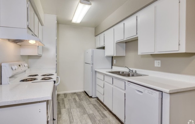 an empty kitchen with white cabinets and a sink and refrigerator