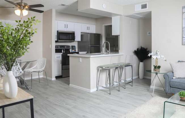 an open kitchen and living room with a bar and stools