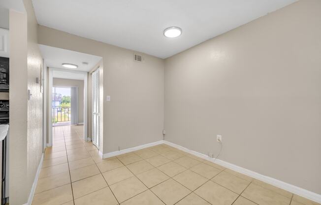 a spacious living room with a tiled floor and a door to a hallway