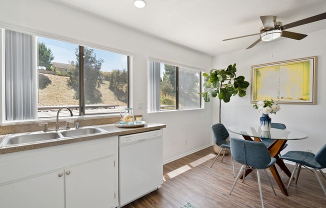 a kitchen with white cabinets and a dining room with a table and chairs