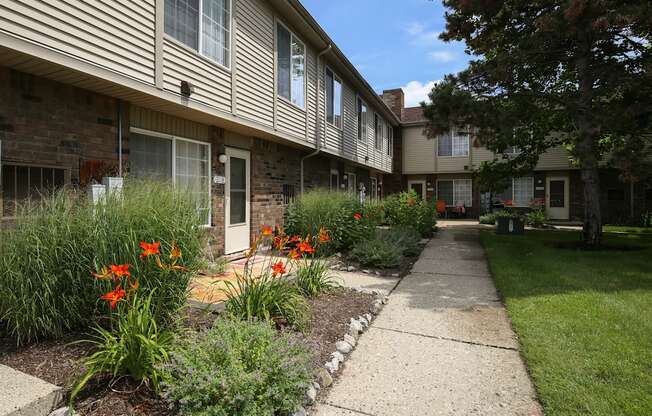 a sidewalk in front of an apartment building with flowers at Village Club of Rochester Hills, Shelby Township, MI 48317