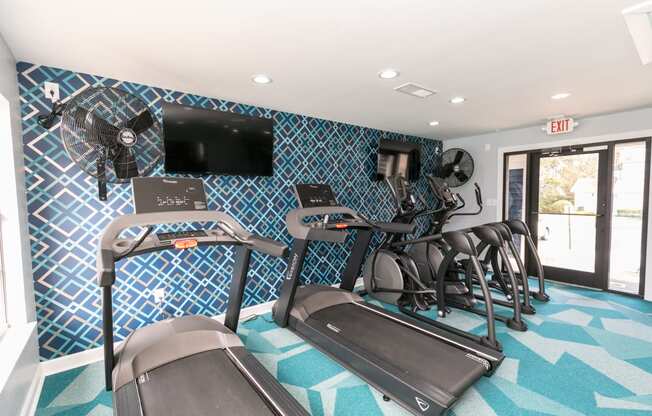 a gym with treadmills and a tv on the wall