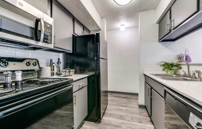 an apartment kitchen with black appliances and white counters