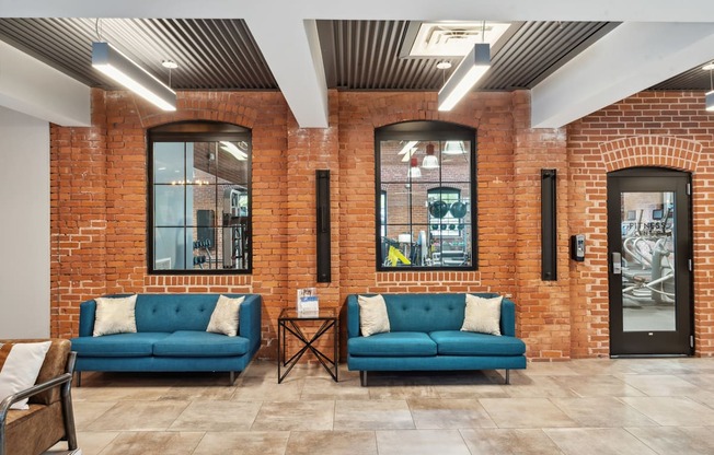a lobby with two blue couches in front of a brick wall at The Tannery, Connecticut, 06033
