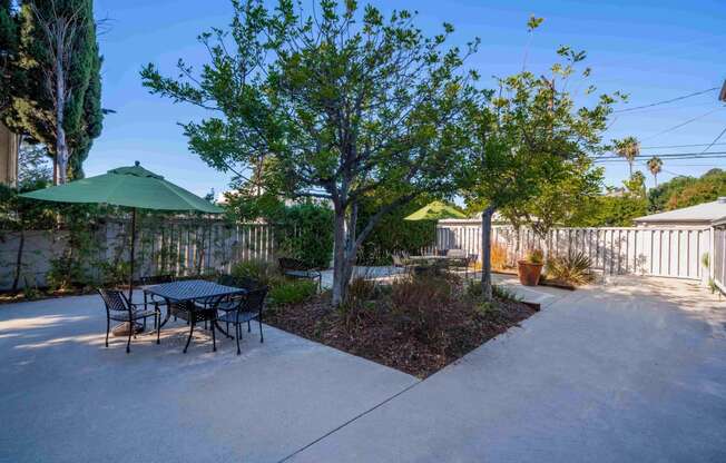 a patio with a table and chairs and a tree