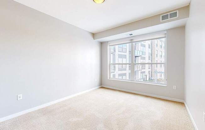 A room with a large window and a carpeted floor.