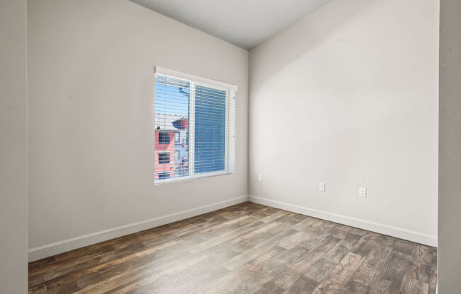 an empty room with a window and wood floors