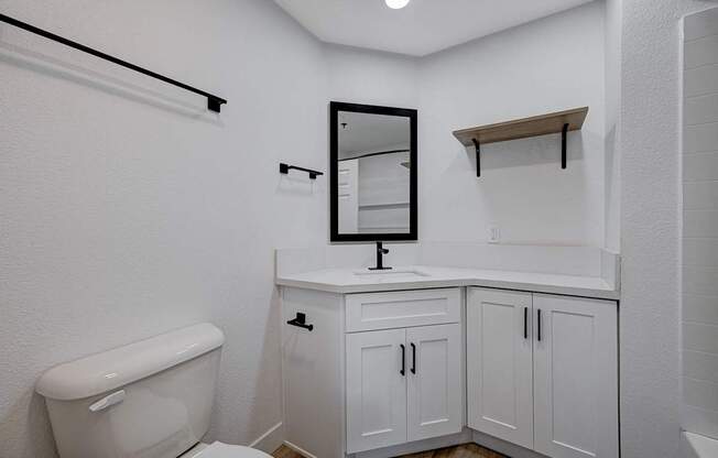 A white bathroom with a toilet, sink, and mirror.