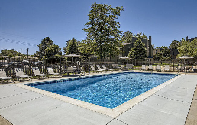 a swimming pool with chairs and trees in the background