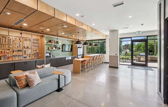 A modern kitchen with a grey couch and wooden cabinets at Link Apartments® CYKEL Apartments, Charlotte, North Carolina