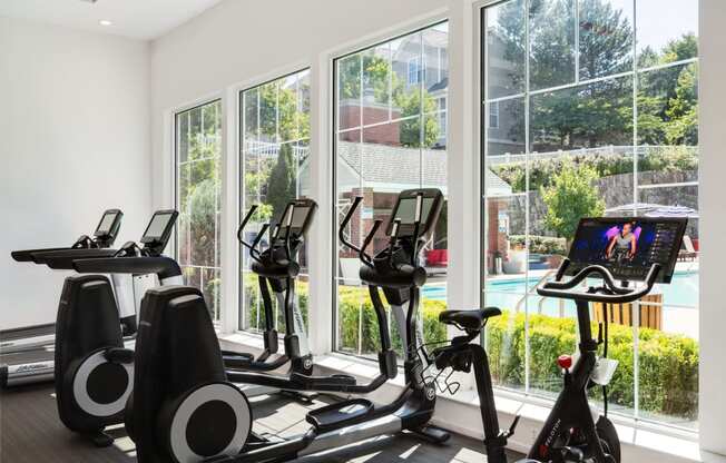 a gym with exercise equipment and windows overlooking a pool at Residences at Stevens Pond, Massachusetts